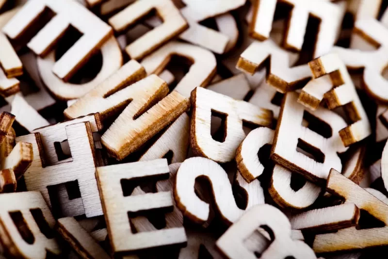 A collection of letters carved out of wood in a big pile.